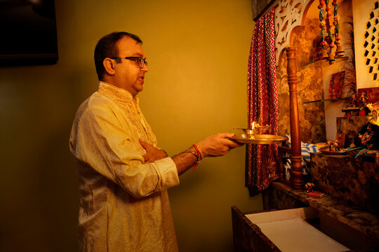 A father performs morning aarti at the home temple with devotion