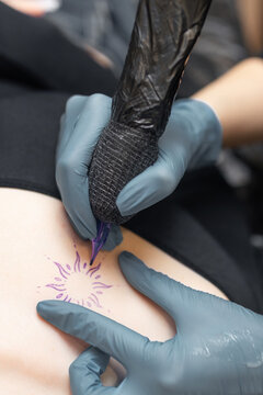 tattoo artist working on a woman chest design in a studio, showing the process of professional tattooing, precision, sterile gloves and cosmetic procedure atmosphere.