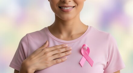 Smiling woman wearing a pink ribbon on her t-shirt, symbolizing breast cancer awareness and hope