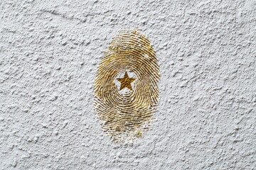 Gold Fingerprint with Star Symbol on Textured Wall