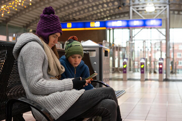 Mother and son using smartphone while waiting at train station