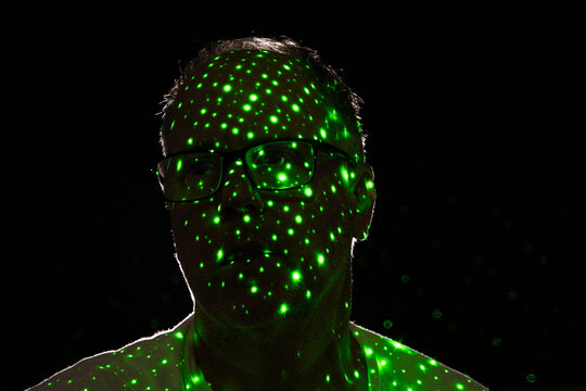 Silhouette of man wearing glasses with green dots on side of face