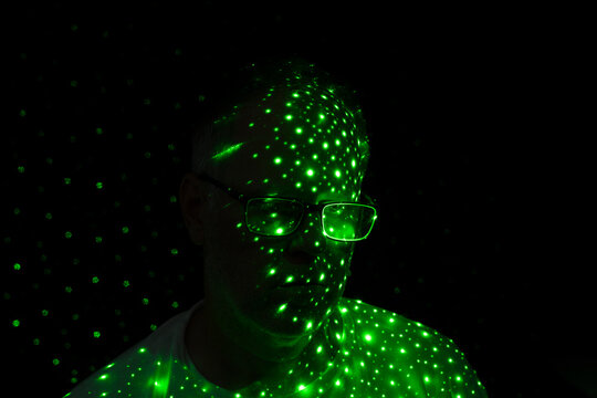 Man covered in green dots of light on black background