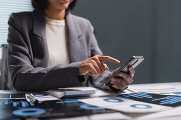 Businesswoman managing financial data using smartphone at desk