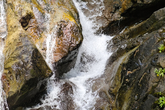 Closeup view of a fast-moving cascade in Mount Rainier National Park, with clear water rushing over rugged rocks and detailed natural textures.