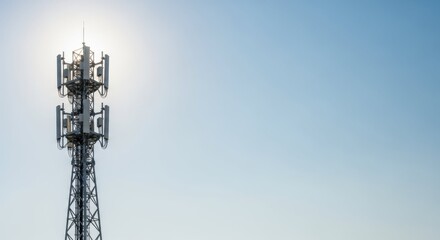 Cellular network communication antenna against bright blue sky creates powerful image. Cellular network infrastructure includes tower, transmitters, and other equipment, making connectivity possible.