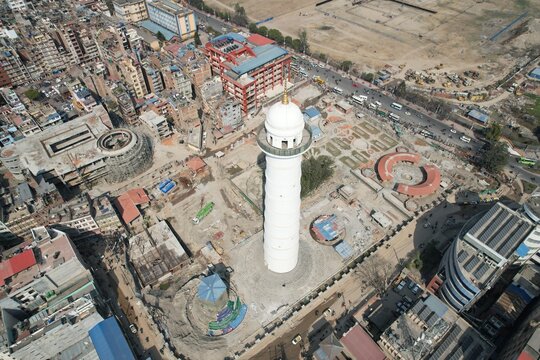 A breathtaking drone view from Dharahara showcases Kathmandu city sprawling beneath, with rooftops, streets, and distant hills illuminated under the soft Himalayan light.