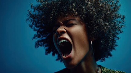 Expressive woman with curly hair yelling passionately in front of a blue background during a creative photo shoot session
