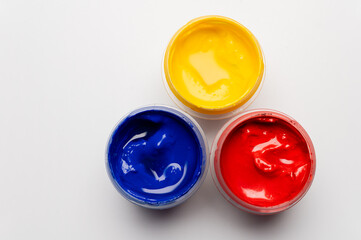 Artist's gouache, top view. Three open bottles of gouache for painting, fresh new paints ready for painting on a white background