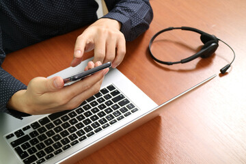 Hands Using Smartphone with Laptop and Headset on Office Desk