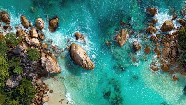 Aerial view of turquoise ocean with large rocks along a rocky coastline and a small sandy beach. Concept Aerial view of turquoise ocean, Turquoise waters along a rocky coastline