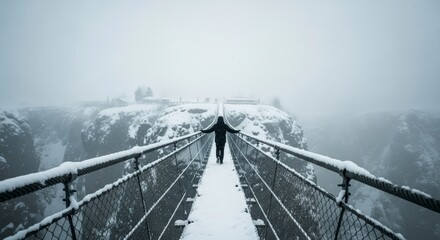 Solitary figure embraces winter's embrace on a snow-covered suspension bridge over a misty canyon