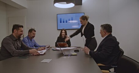 Businesspeople in a meeting discuss company strategy and analyze market trends using data presented on a screen. - Powered by Adobe