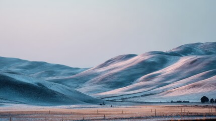 Rolling snow covered hills under a pale sky at dawn landscape winter