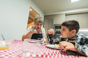 Family enjoying dinner, mother and child having a meal at kitchen table. Candid moment of daily life indoors