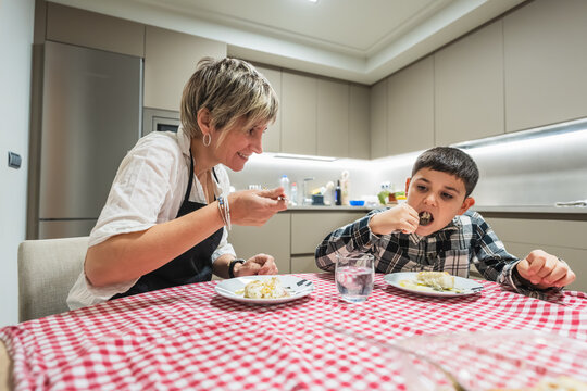 Mother and child sharing a meal in a modern kitchen, focusing on bonding and family lifestyle moments
