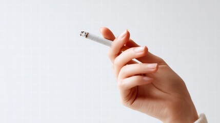 A hand gracefully holds a lit cigarette, with smoke gently rising against a white backdrop.