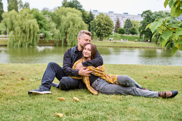 Young couple embracing by lake in urban park on autumn day