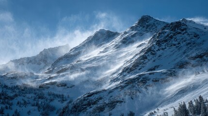 Snow covered mountain peaks with wind blowing snow across slopes winter