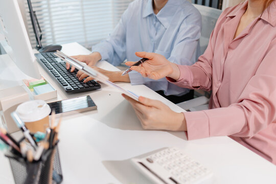 Two female colleagues discussing business reports together in a modern office environment, representing teamwork, data analysis, and collaboration in a start-up company setting.