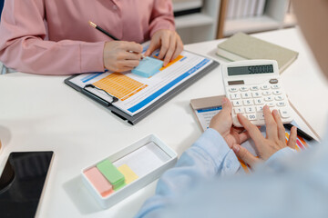 Two female colleagues discussing business reports together in a modern office environment, representing teamwork, data analysis, and collaboration in a start-up company setting.