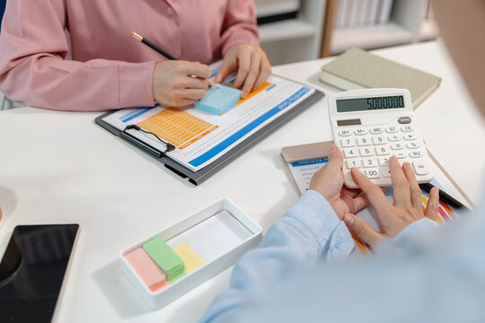 Two female colleagues discussing business reports together in a modern office environment, representing teamwork, data analysis, and collaboration in a start-up company setting.