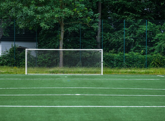 Fototapeta premium Blick auf einen Fußballplatz mit Kunstrasen während einer Trainingseinheit mit einem am Ende der Spielfläche - viel copy space