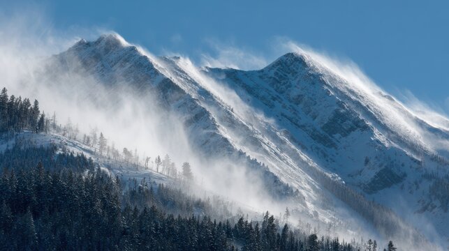 Snow covered mountain peaks with wind blowing snow and evergreen trees winter