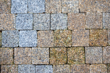 Close-up of textured stone pavement made of small square granite blocks arranged in an interlocking pattern.
