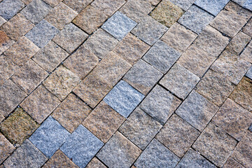 Close-up of textured stone pavement made of small square granite blocks arranged in an interlocking pattern.