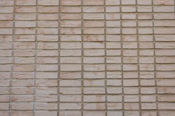 Close-up of a beige brick wall with a uniform rectangular pattern used in exterior construction.