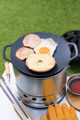 黒いマルチグリドルと具材のクローズアップ、芝生の緑を背景に