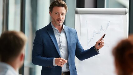 Male business coach presenting strategies at a corporate workshop using a flipchart in a modern conference room during daylight hours - Powered by Adobe