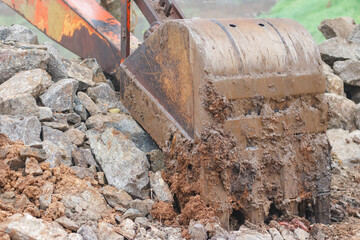 Muddy Excavator Bucket Working on Rocky Terrain