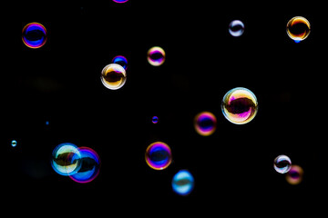 Colorful Soap Bubbles with Blue, Purple, Pink, Gold, and Iridescent Tones on Black Background - Abstract Bubble Photography Showing Multiple Floating Spheres with Dynamic Light Reflections

