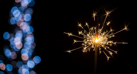 A close-up of bright sparkler against black backdrop with bokeh effect, representing celebration, festivity, or memorable occasion, perfect for holiday event