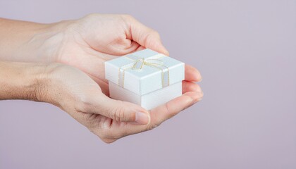 Elegant white gift box with golden ribbon held gently in hands, a symbol of love, appreciation, and thoughtful giving for birthdays and special occasions