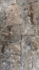 A close-up view of a rustic stone wall with weathered texture and natural stone patterns.
