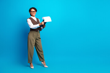 Young female professional presenting a document against a bright blue background in a stylish office setting