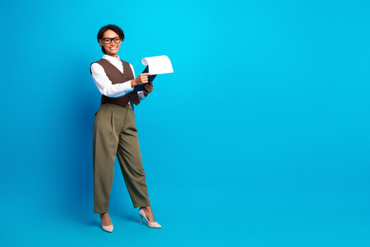 Young female professional presenting a document against a bright blue background in a stylish office setting
