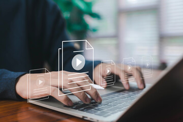 Hands typing on a laptop with floating video file icons represent digital content creation, online media management, video production, multimedia workflow, and modern content marketing strategies.
