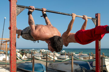 Two men performing back lever exercise outdoors