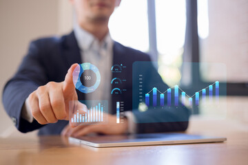 Businessman analyzing financial data with interactive hologram charts and graphs on tablet, representing business analytics, data visualization digital finance smart investment, and market insight.