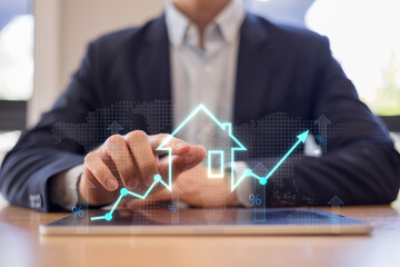 Real estate investor analyzing property growth and interest rate trends on tablet with digital graph interface. Housing market investment financial technology concept.