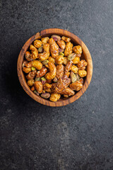 Nuts coated in sugar glaze in bowl on black table. Top view.