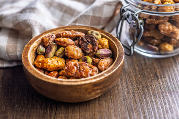 Nuts coated in sugar glaze in bowl on wooden table.