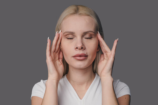 serene woman gently pressing forehead, woman with closed eyes practicing gentle facial release techniques