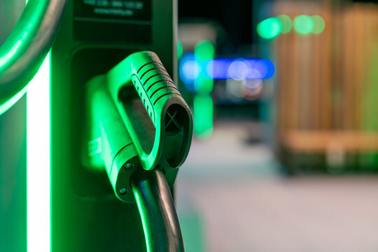 Beleuchtete Lades&auml;ule mit Ladekabel einer Stromtankstelle f&uuml;r Elektroautos in der Nacht