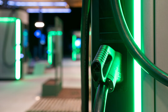 Beleuchtete Lades&auml;ule mit Ladekabel einer Stromtankstelle f&uuml;r Elektroautos in der Nacht