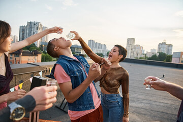 Young friends celebrate friendship and fun during a rooftop party at sunset in the city